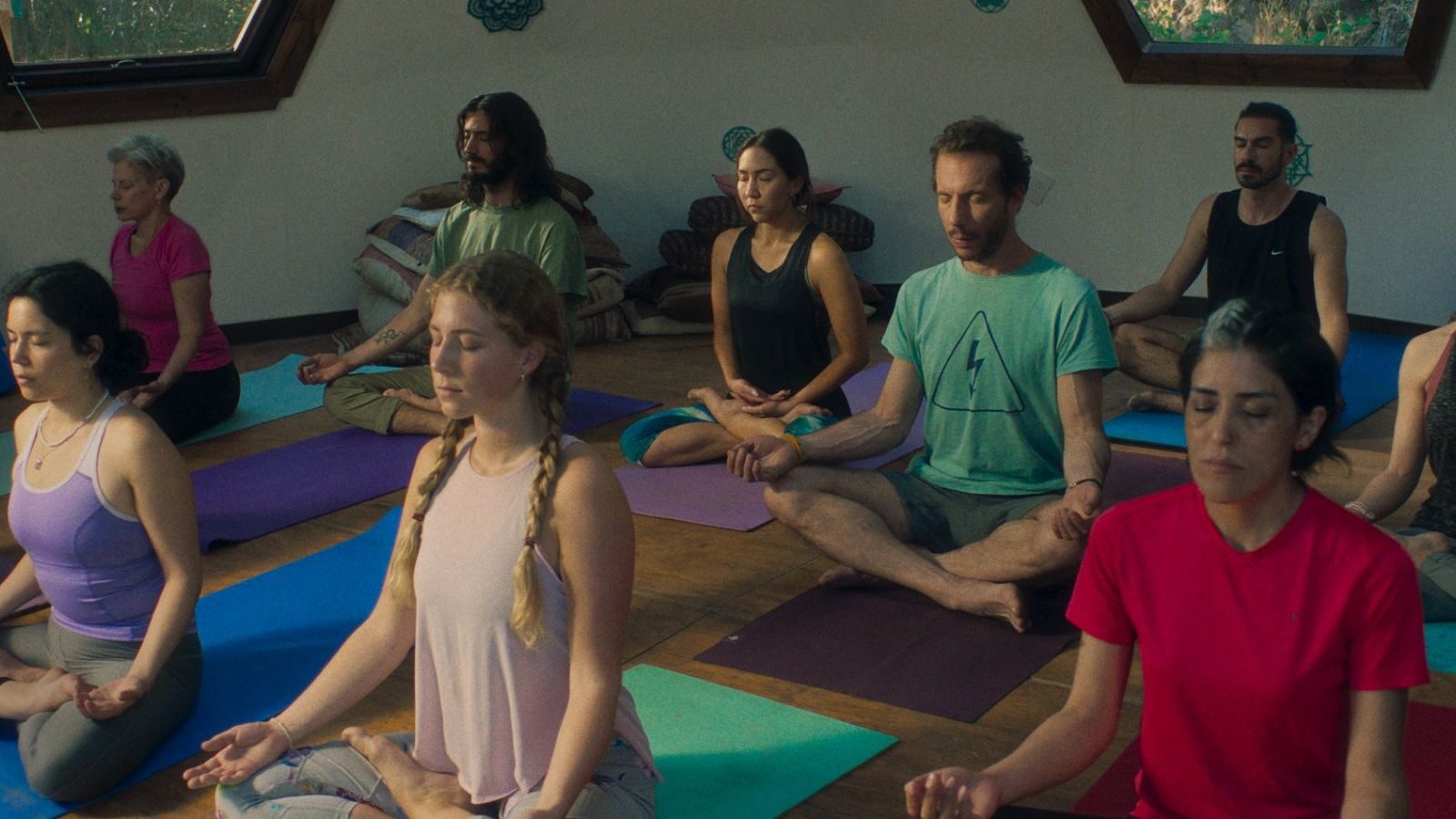 Celine Wempe in a yoga class scene from 'La Práctica' (2023), performing a yoga pose alongside other participants in a peaceful studio setting.